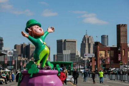 A parade float with a leprechaun holding his arms wide on a pink pot of gold at the Detroit St. Patrick’s Day Parade. 