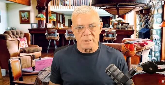 Man speaking into a microphone, with a luxurious living room blurred in the background.