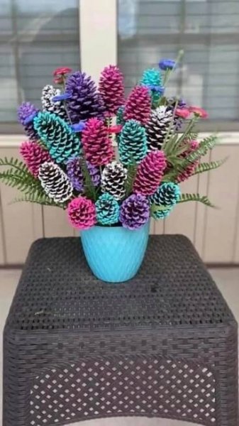 a blue vase filled with purple and green pine cones