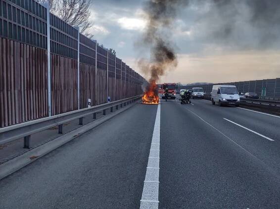 Fotografie hořícího automobilu na dálnici.