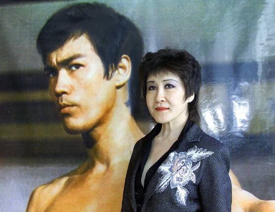 Actress Betty Ting Pei poses next to a poster of Bruce Lee circa 2003