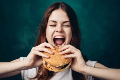 Woman getting ready to bit into a hamburger.