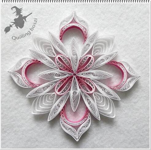 an ornament made out of paper with pink and white designs on the front