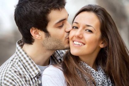 Download - Close up portrait of boy kissing girlfriend on cheek outdoors. — Stock Image