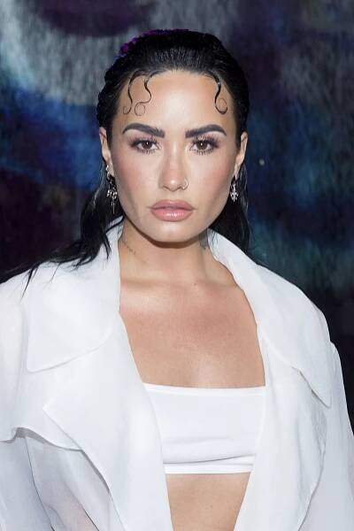 Demi Lovato with curly hair and a white jacket at the Boss Spring/Summer 2023 collection presentation at Herald Plaza in Miami