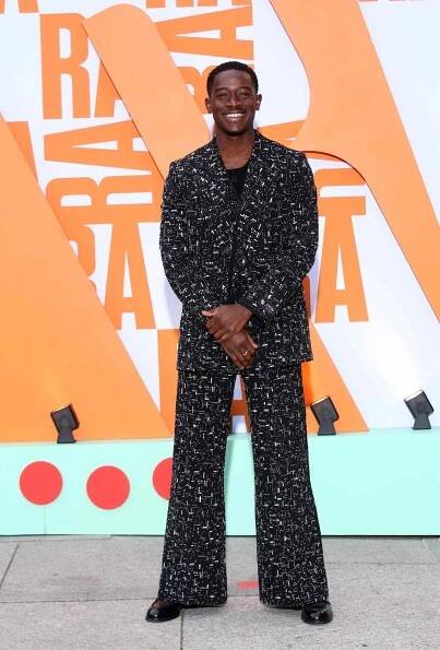Damson Idris standing in front of an abstract background